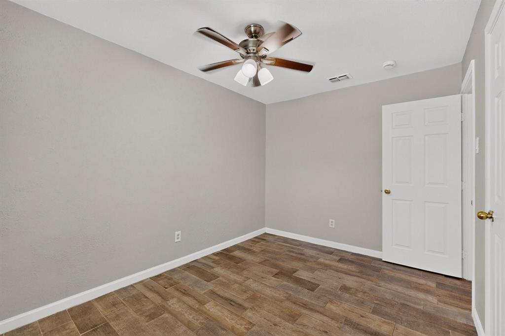 A cozy third bedroom with a ceiling fan, closet and hardwood floors.