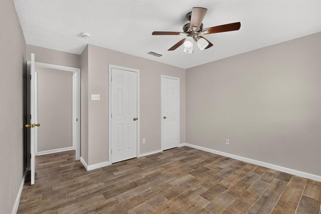 Bright primary bedroom with a ceiling fan, hardwood floors and two separate closets, perfect for relaxation.