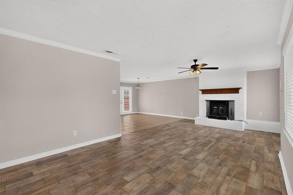 A spacious living room featuring hardwood floors, a fireplace and a ceiling fan, ready for new furnishings and decor. A spacious living room featuring hardwood floors, a fireplace and a ceiling fan, ready for new furnishings and decor.