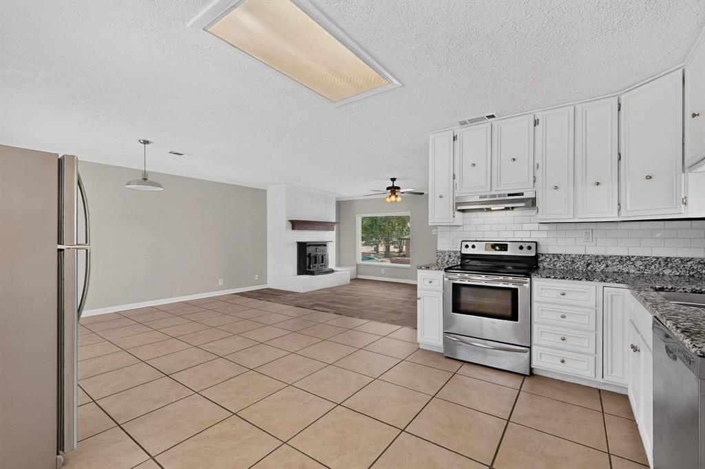 Bright kitchen with sleek white cabinets, stainless steel appliances and tile flooring, creating a clean and modern atmosphere.