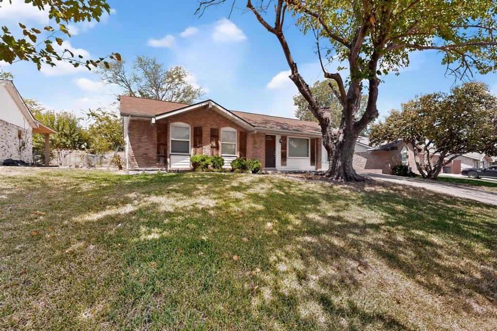 A lovely brick residence with a wide yard and a mature tree, offering a peaceful and inviting outdoor space.