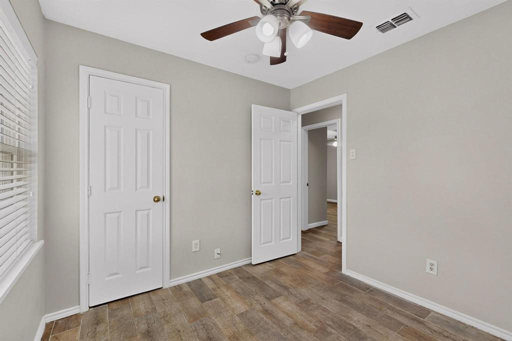 A cozy second bedroom featuring a ceiling fan, closet and a window letting in natural light.