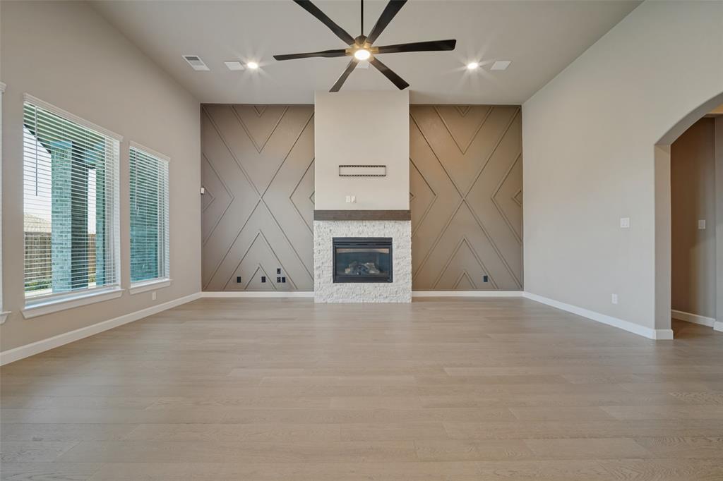 The living room features the same beautiful wood-look flooring, accent walls bookending a cozy fireplace, and flooded in natural light