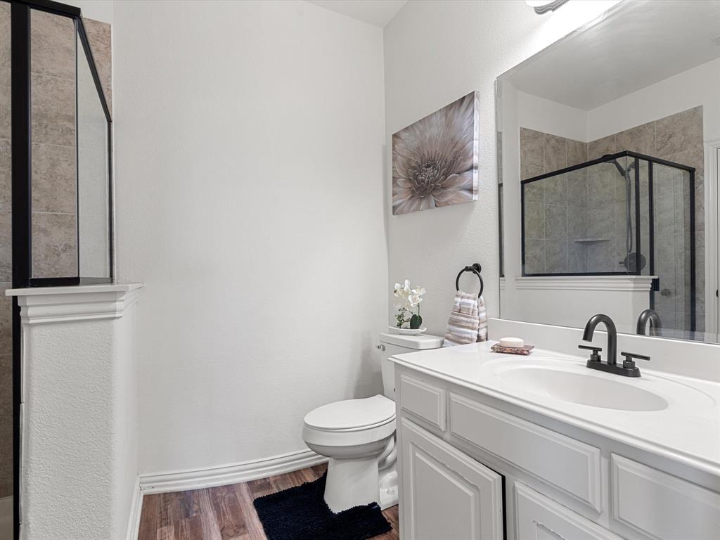 Bathroom with dark wood finished floors, a shower stall, vanity, and a textured wall