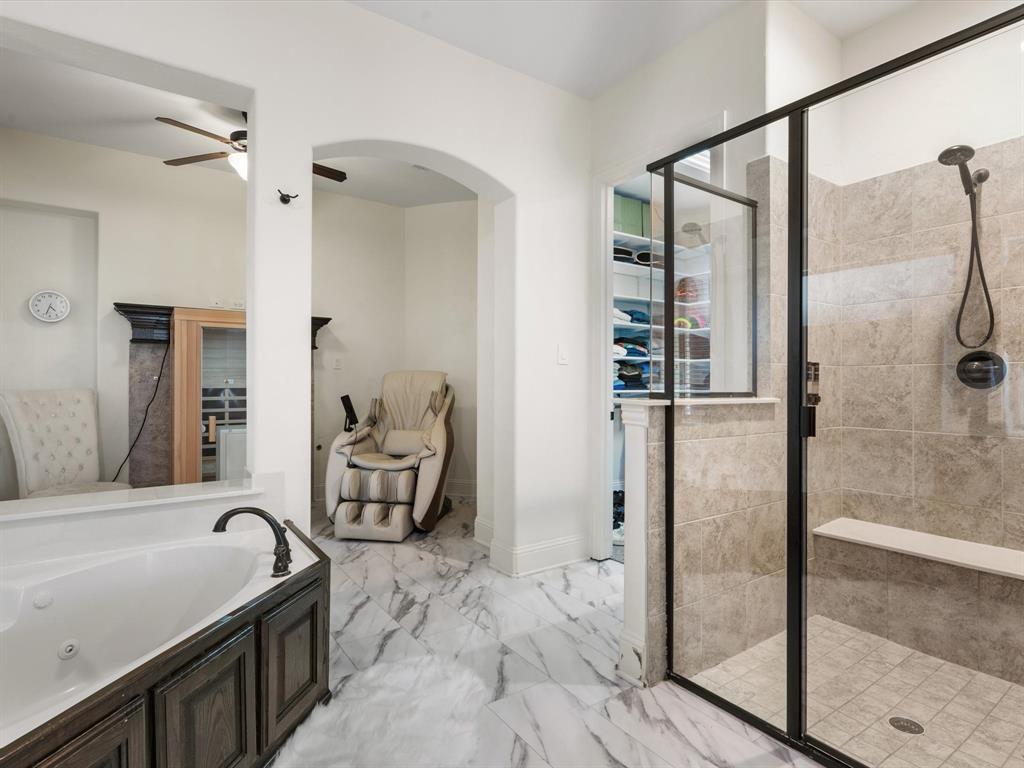 Bathroom with a shower stall, a walk in closet, a jetted tub, light marble finish floors, and a ceiling fan