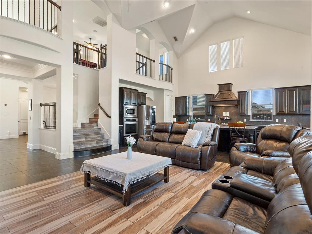 Living room with a ceiling fan, high vaulted ceiling, wood finish floors, recessed lighting, and stairway