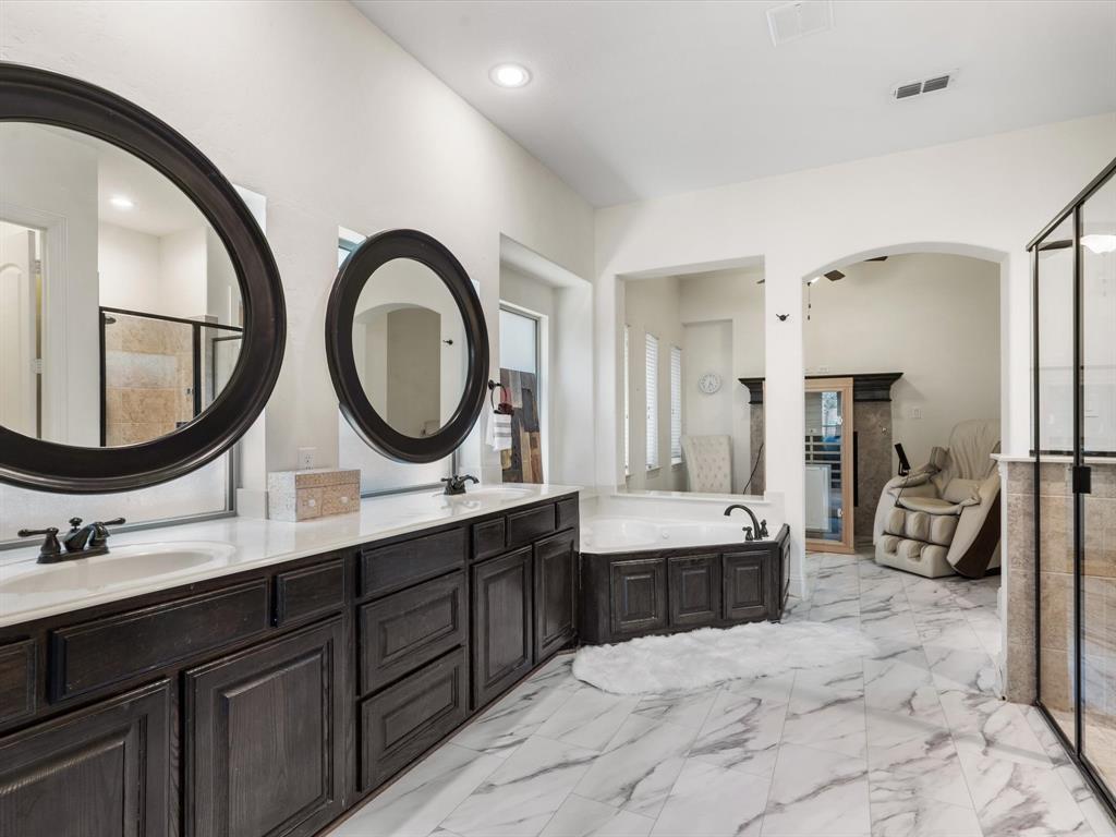Full bathroom with a shower stall, light marble finish flooring, double vanity, and a bath