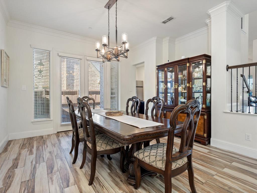 Dining room with light wood-type flooring, crown molding, and a chandelier