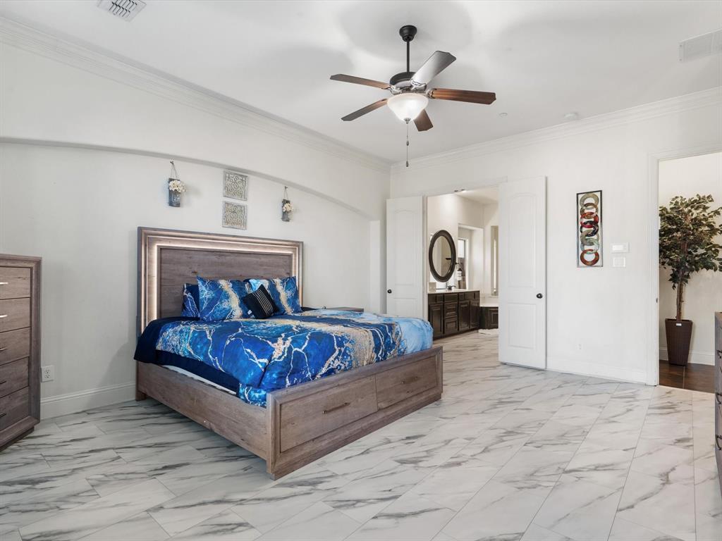 Bedroom featuring ornamental molding, light marble finish flooring, a ceiling fan, and ensuite bath