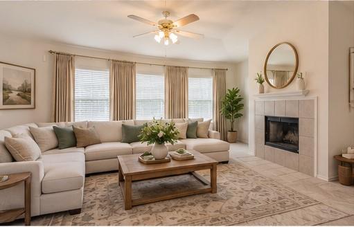 Living area featuring a tile-surround fireplace with a mantel, vaulted ceilings, multi-panel window configuration, and a ceiling fan with integrated lighting