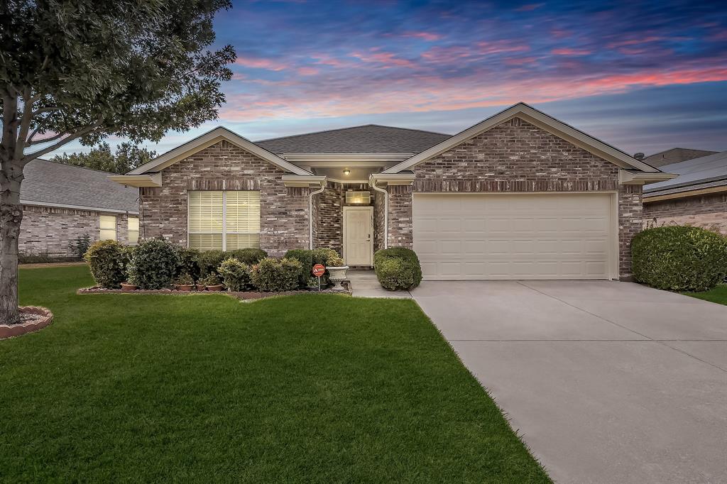 Brick exterior featuring a multi-gabled roofline, concrete driveway, and established landscaping