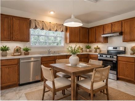Kitchen featuring wood cabinetry, stainless steel appliances, white solid-surface countertops, pendant lighting, and tile flooring