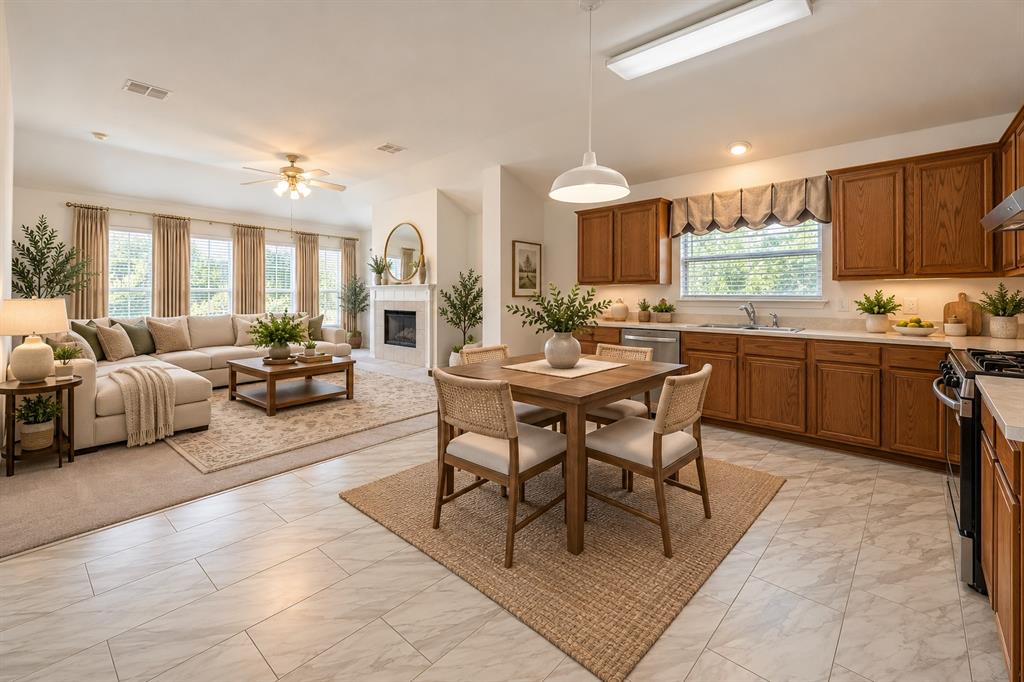 Open-concept interior featuring wood-finish cabinetry, stone-patterned tile flooring, a fireplace with a mantel, and large picture windows