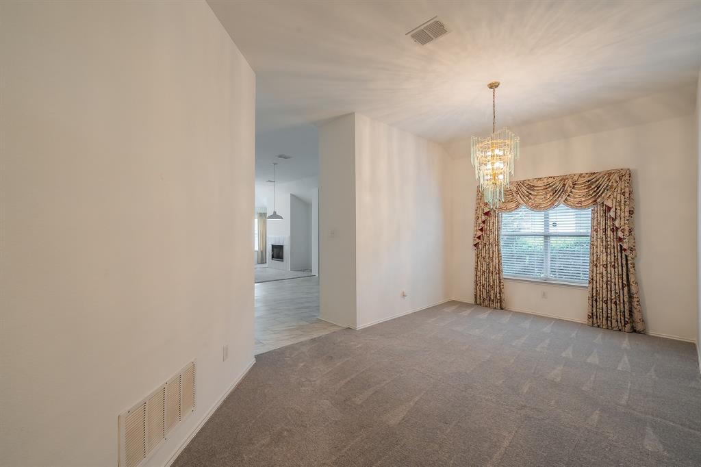Formal room featuring neutral carpeting, a tiered crystal chandelier, and a large window