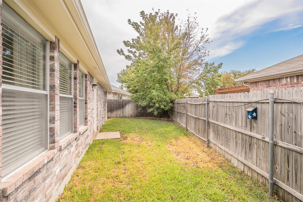 Exterior side yard featuring brick masonry, horizontal wood fencing, and mature trees