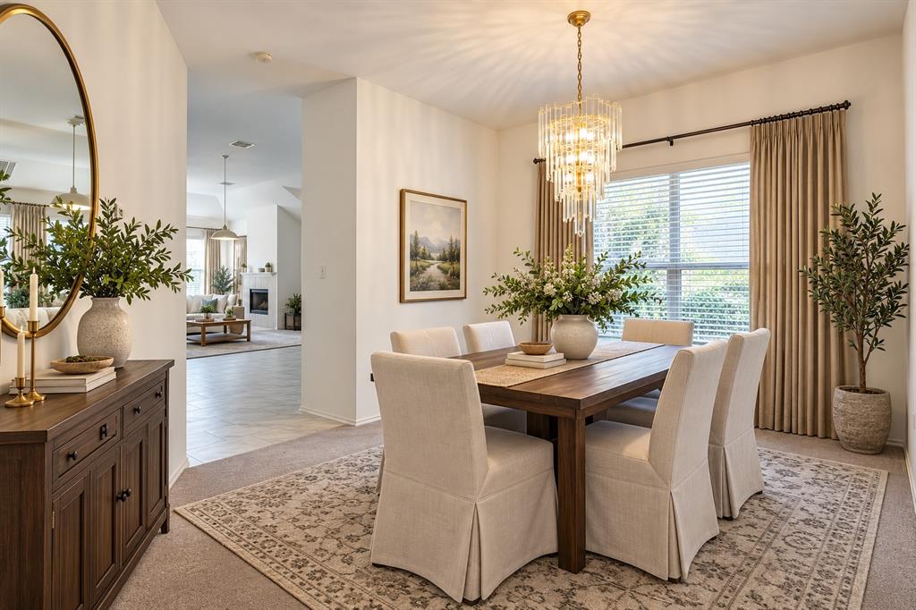 Dining area featuring a tiered crystal chandelier, neutral wall-to-wall carpeting, and a large window with floor-to-ceiling drapery
