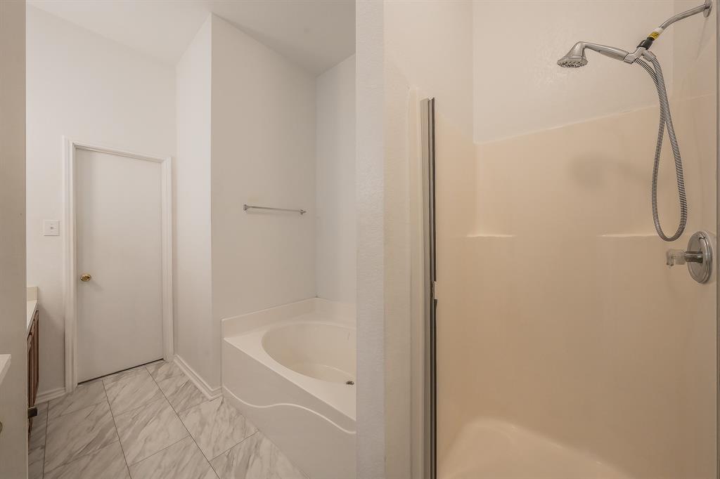 Bathroom featuring a separate soaking tub, walk-in shower with a handheld fixture, tile flooring, and a wall-mounted towel bar