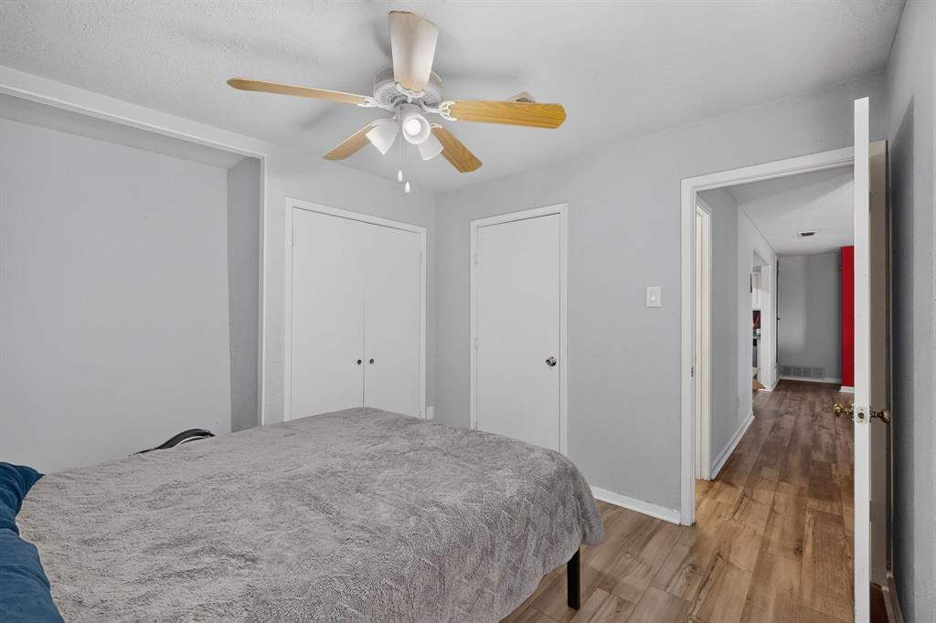 Interior room featuring wood-finish flooring, a ceiling fan with integrated lighting, and dual closet storage