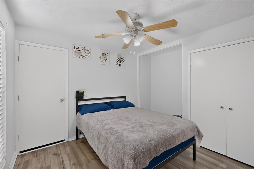Room featuring wood-finish flooring, a ceiling fan with integrated lighting, a recessed alcove, and a double-door closet