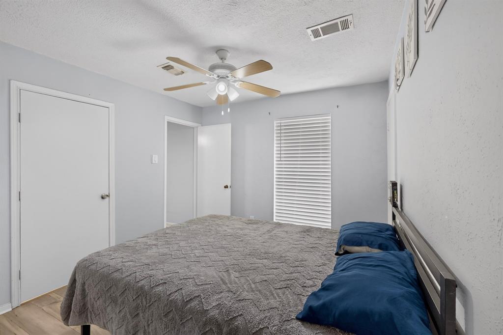 Neutral-toned walls paired with wood-finish flooring, featuring a ceiling fan with integrated lighting and horizontal window blinds