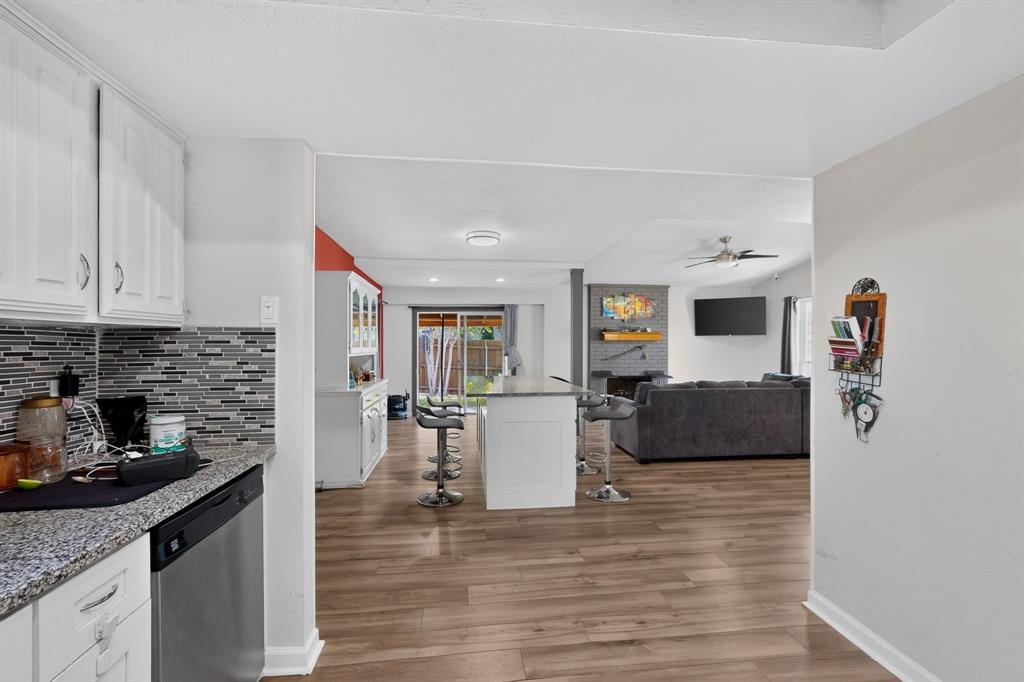 Kitchen featuring white cabinetry, stone-finish countertops, and a multi-toned tile backsplash