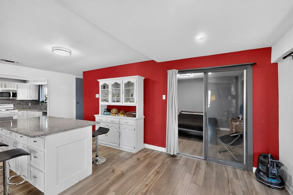 Kitchen featuring a stone-topped central island, built-in white cabinetry, wood-finish flooring, and sliding glass doors