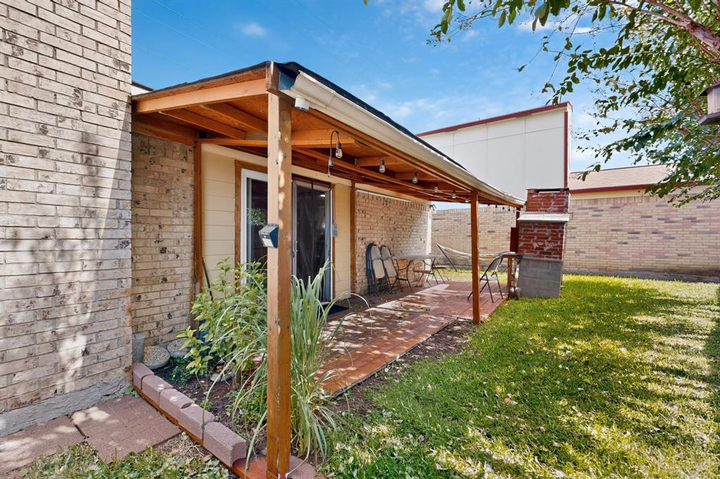 Covered patio featuring wood-frame construction, brick exterior walls, masonry flooring, and a built-in outdoor masonry fireplace