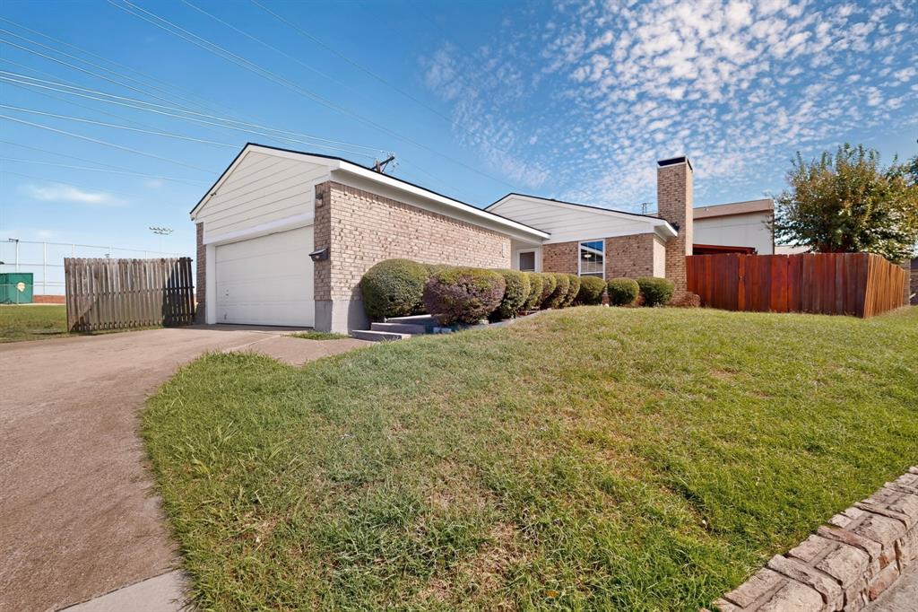 Exterior featuring a brick and horizontal siding facade, a two-car garage, an attached masonry chimney, and wood perimeter fencing