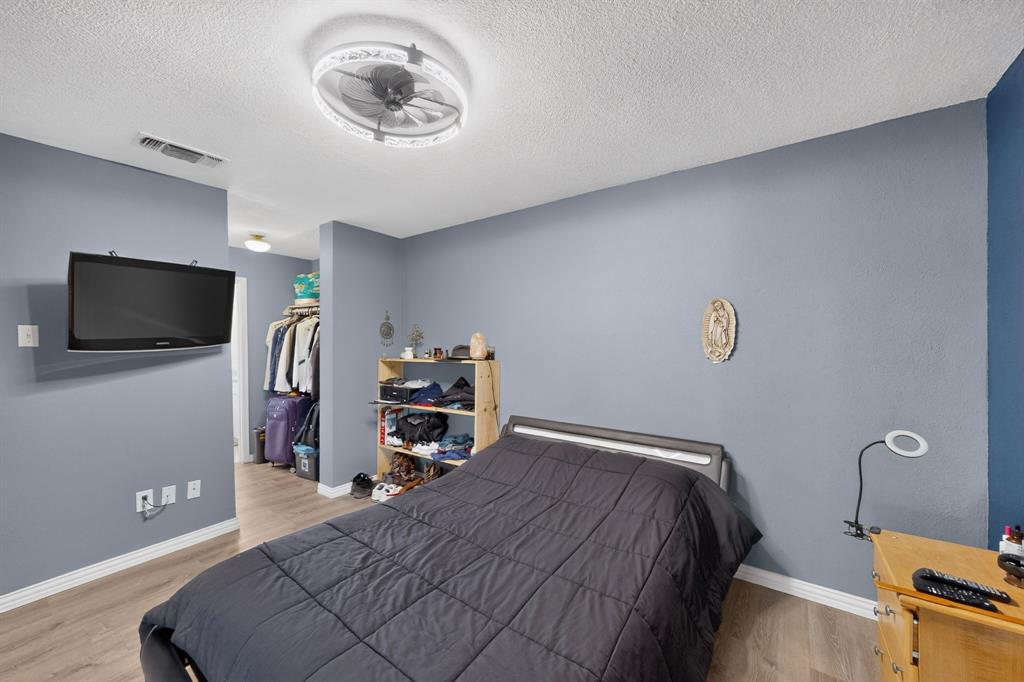 Neutral-toned interior featuring wood-finish flooring, textured walls, and a contemporary ceiling fan with an integrated light fixture