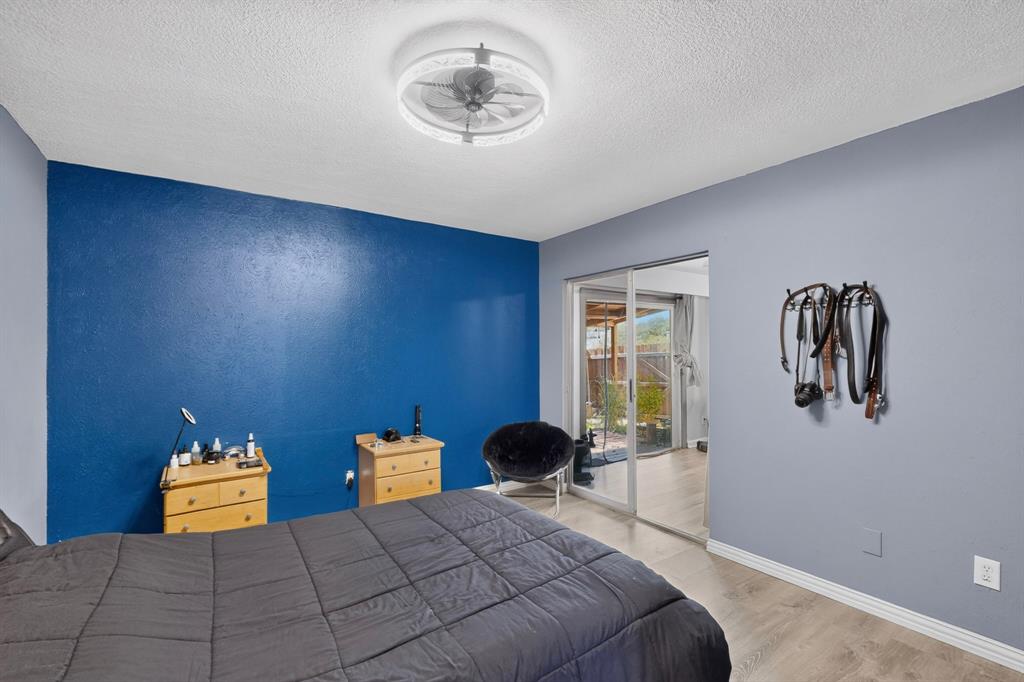Room featuring wood-finish flooring, sliding glass door, and a circular ceiling fan with integrated lighting