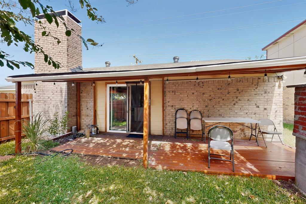Rear exterior featuring a brick chimney, a wood-finish patio deck, and a covered pergola