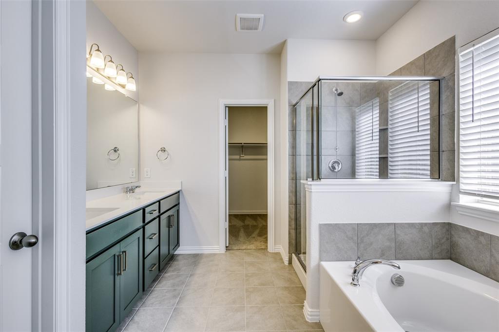 Bathroom featuring tile patterned floors, a spacious closet, a shower stall, double vanity, and a garden tub