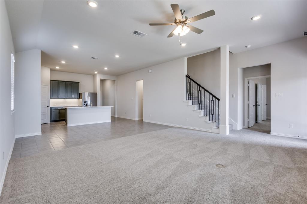 Unfurnished living room with a ceiling fan, visible vents, baseboards, light colored carpet, and recessed lighting