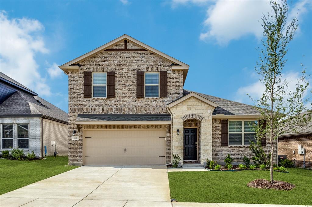 View of front of home featuring concrete driveway, a front yard, brick siding, and a garage