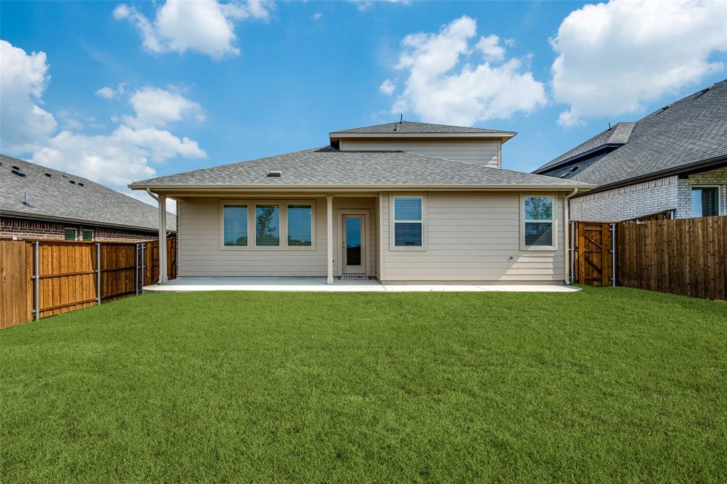 Back of house featuring a yard, a patio, a shingled roof, and a fenced backyard