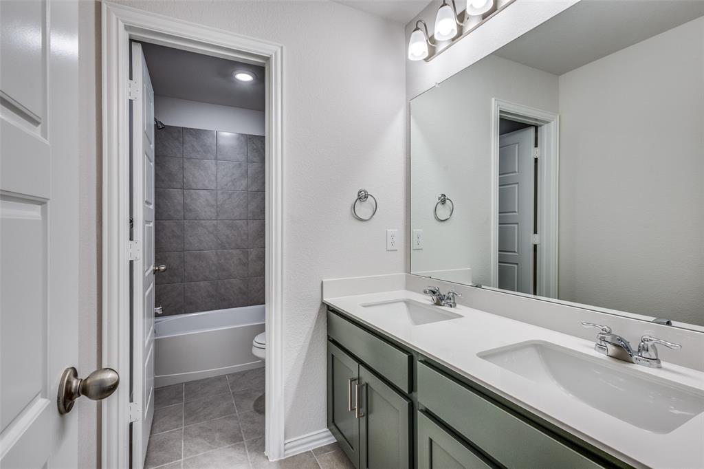 Full bath featuring toilet, tile patterned flooring, double vanity, and a sink