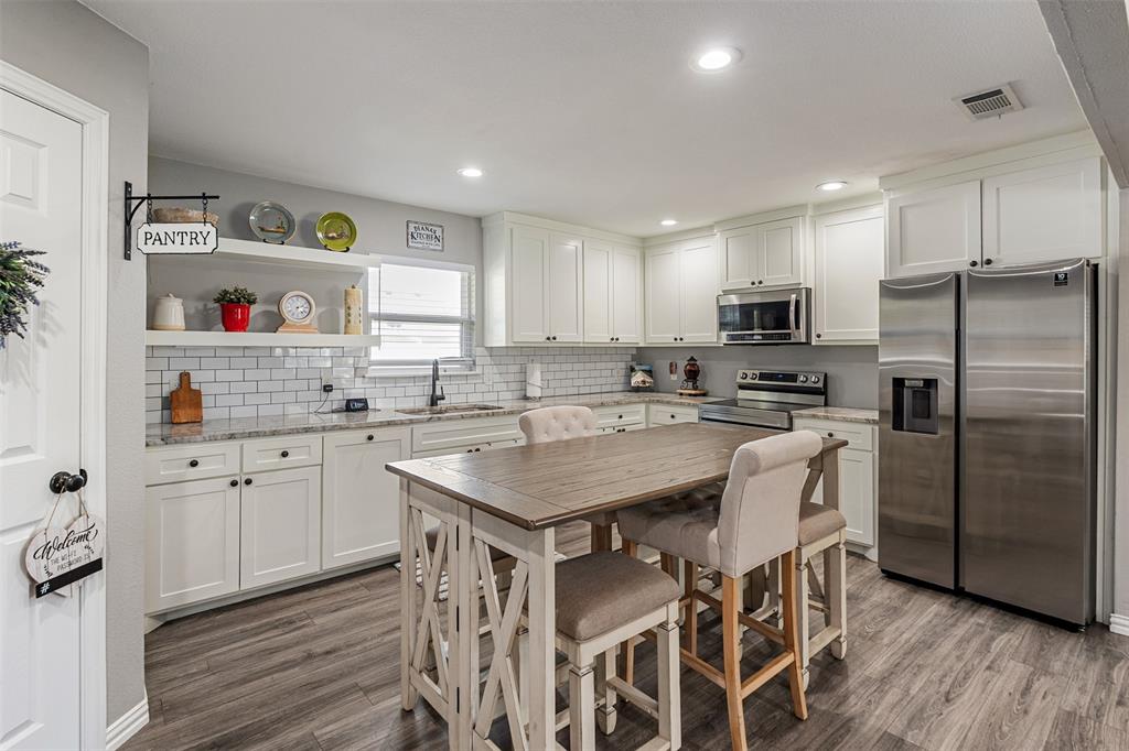 Kitchen featuring white shaker-style cabinetry, stone-finish countertops, subway tile backsplash, recessed lighting, and wood-finish flooring