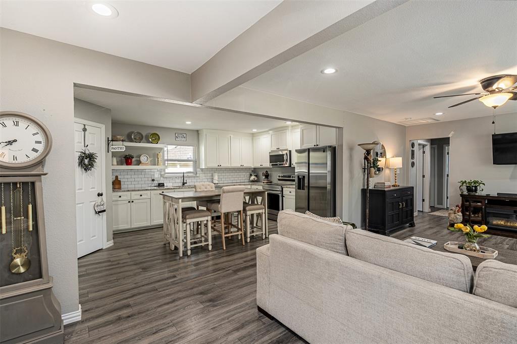 Kitchen featuring white cabinetry, subway tile backsplash, stainless steel appliances, and a central island, with wood-finish flooring throughout the space Kitchen featuring white cabinetry, subway tile backsplash, stainless steel appliances, and a central island, with wood-finish flooring throughout the space