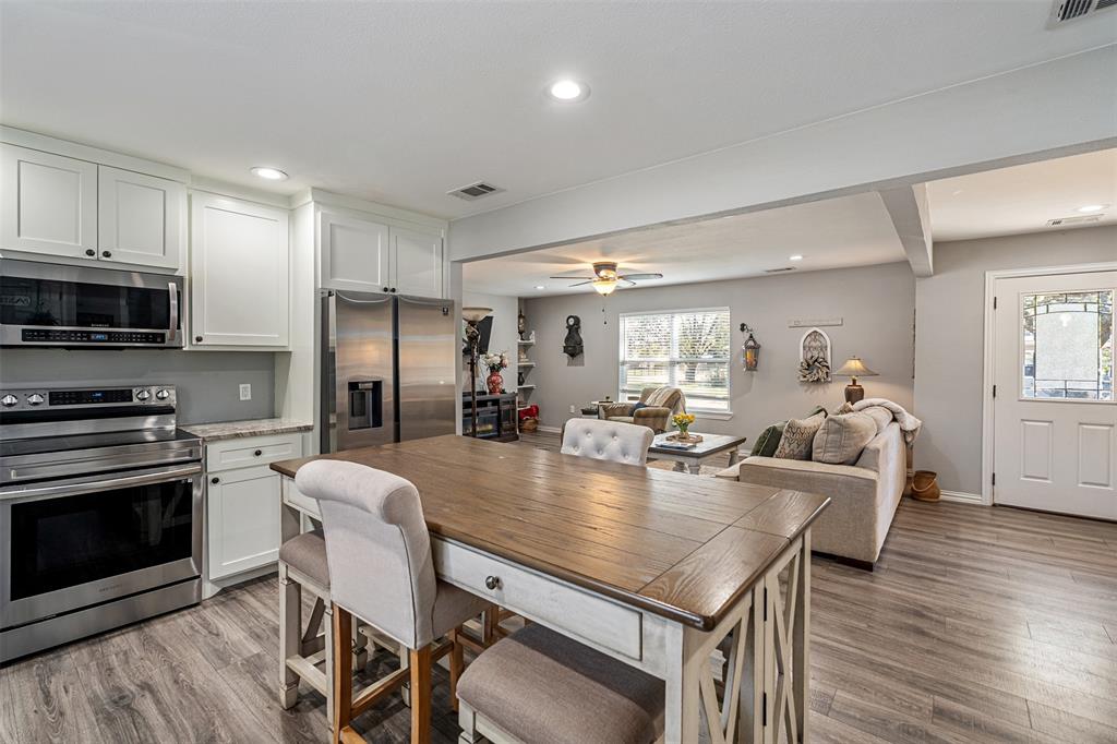 Kitchen featuring white shaker-style cabinetry, stainless steel appliances, and wood-finish flooring throughout the space