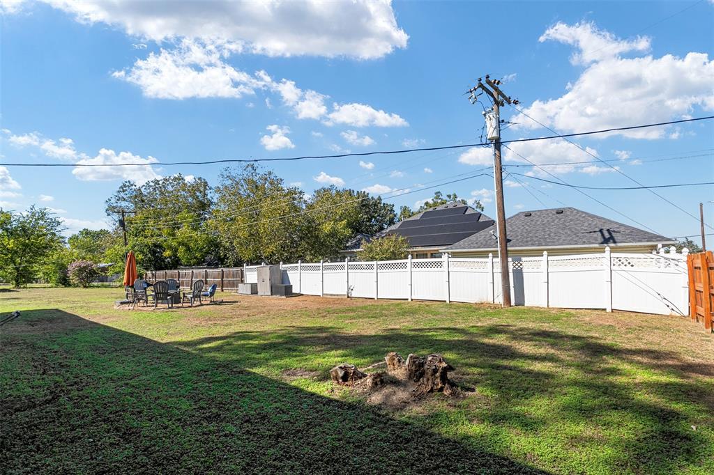 Expansive backyard featuring a white lattice-top vinyl privacy fence and roof-mounted solar panels
