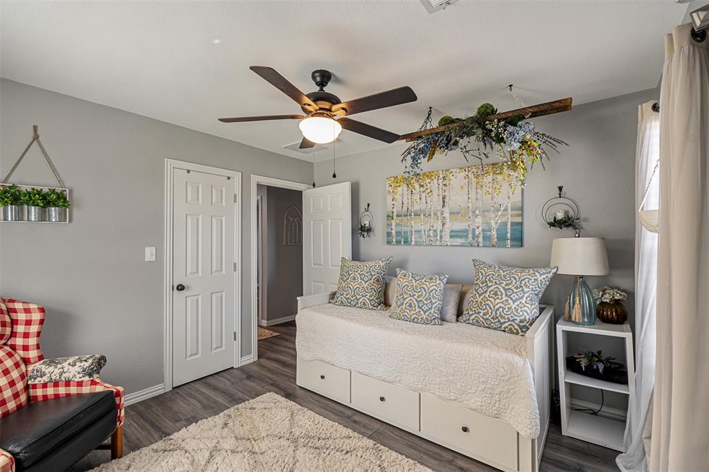 Room featuring wood-finish flooring, a multi-blade ceiling fan with integrated lighting, and two six-panel interior doors