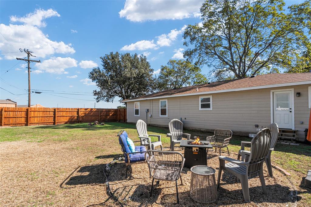 Backyard featuring a wood privacy fence, exterior siding, and a designated gravel fire pit area