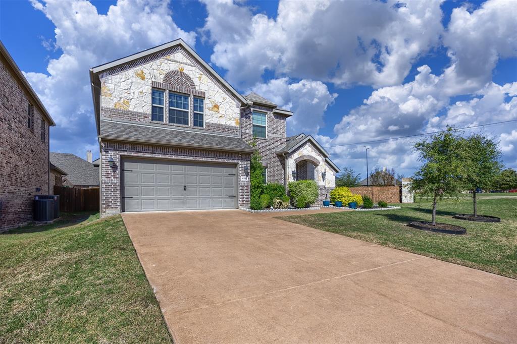 Two-story residence featuring brick and stone veneer masonry, a multi-gabled roofline, an attached two-car garage, and a concrete driveway