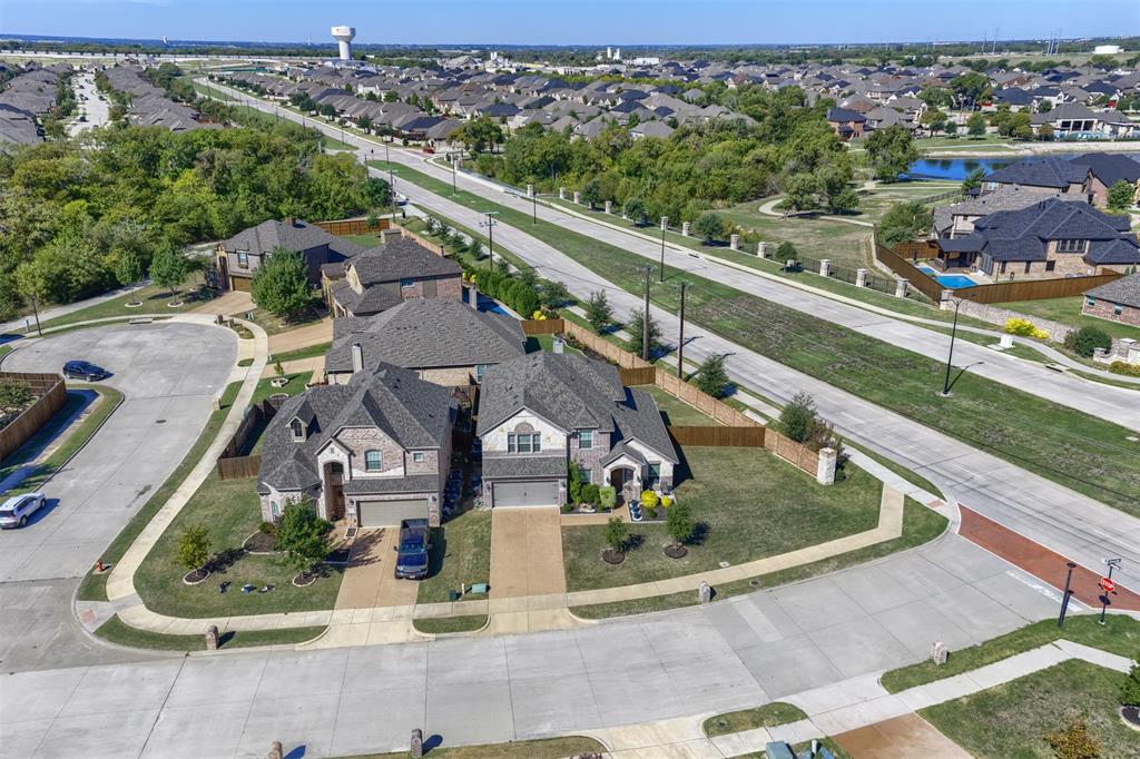 Aerial perspective of a multi-story brick residence situated on a corner lot, featuring a multi-gable asphalt shingle roof, attached multi-car garages, and concrete driveways