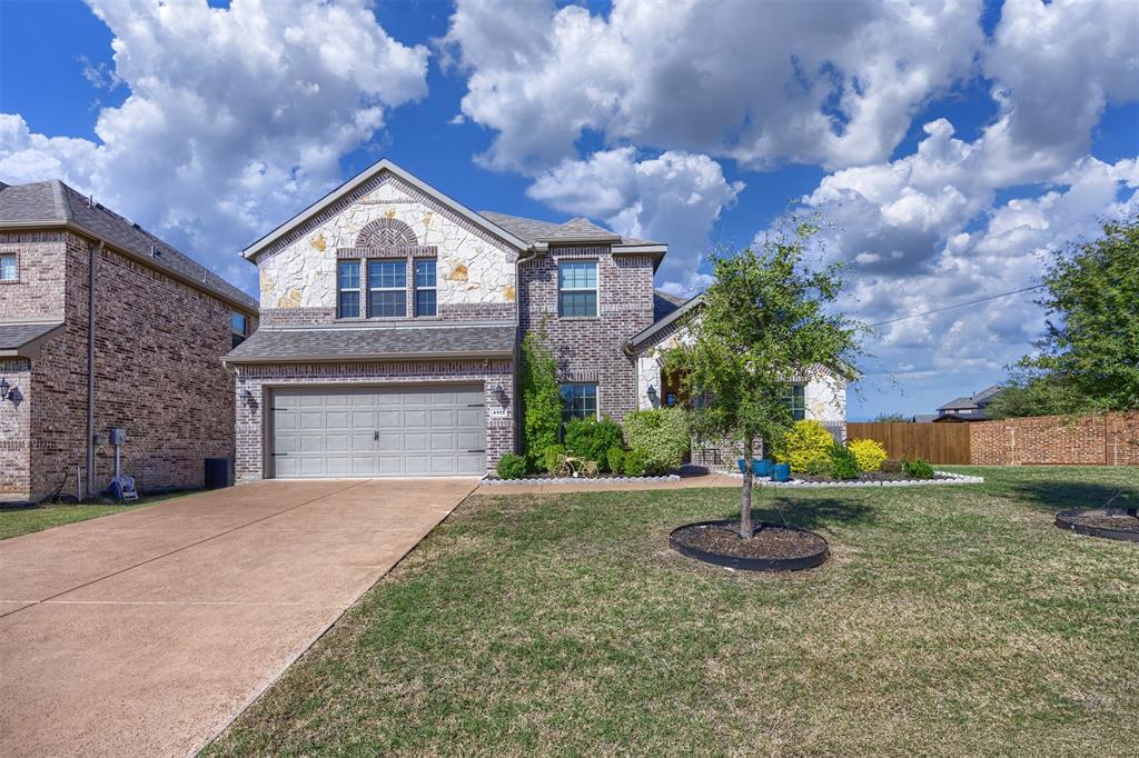Two-story residence featuring a mixed brick and stone facade, concrete driveway, and attached two-car garage