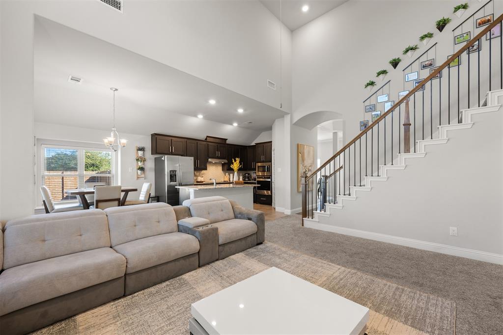 Vaulted ceilings, open-concept floor plan, kitchen featuring dark-stained cabinetry and a center island, and a staircase with metal balusters and a wood handrail
