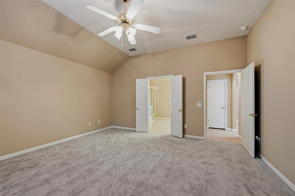 Vaulted ceilings featuring a central overhead fan, neutral wall finishes, plush wall-to-wall carpeting, and double-door entryways