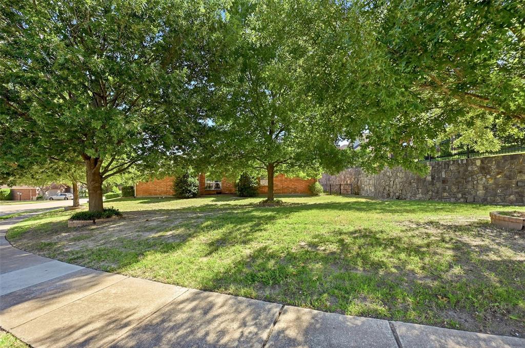 Expansive lawn featuring mature trees and a substantial stone retaining wall