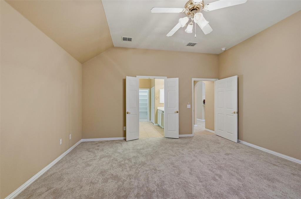 Vaulted ceiling room featuring neutral carpeting, a multi-light ceiling fan, and double-panel entry doors