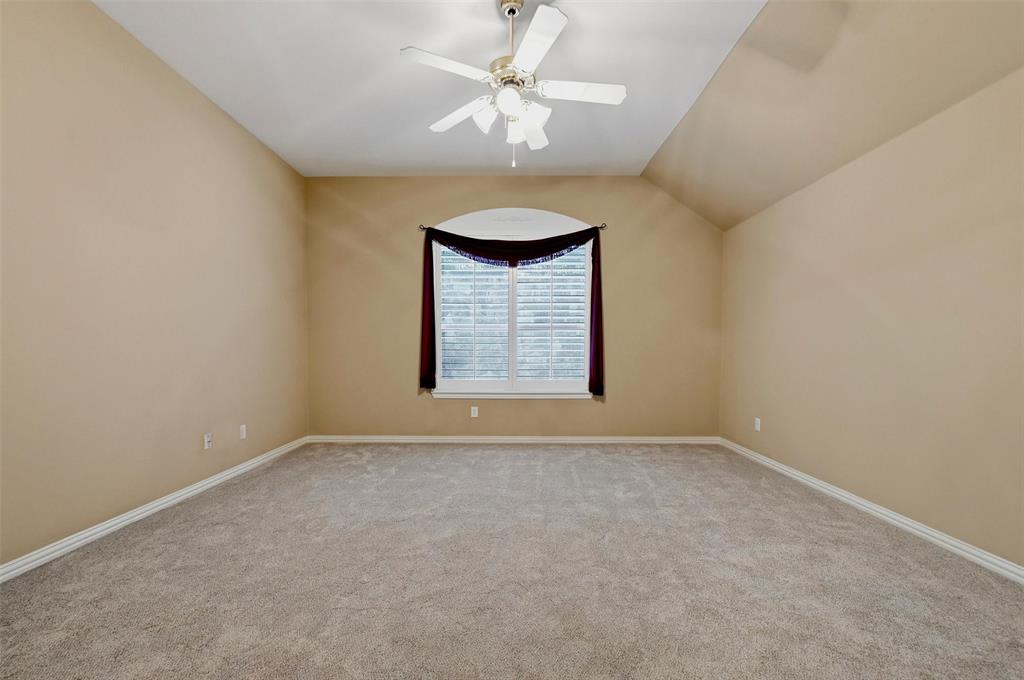 Owner's suite, featuring vaulted ceiling, carpeting, ceiling fan with integrated lighting, and an arched window